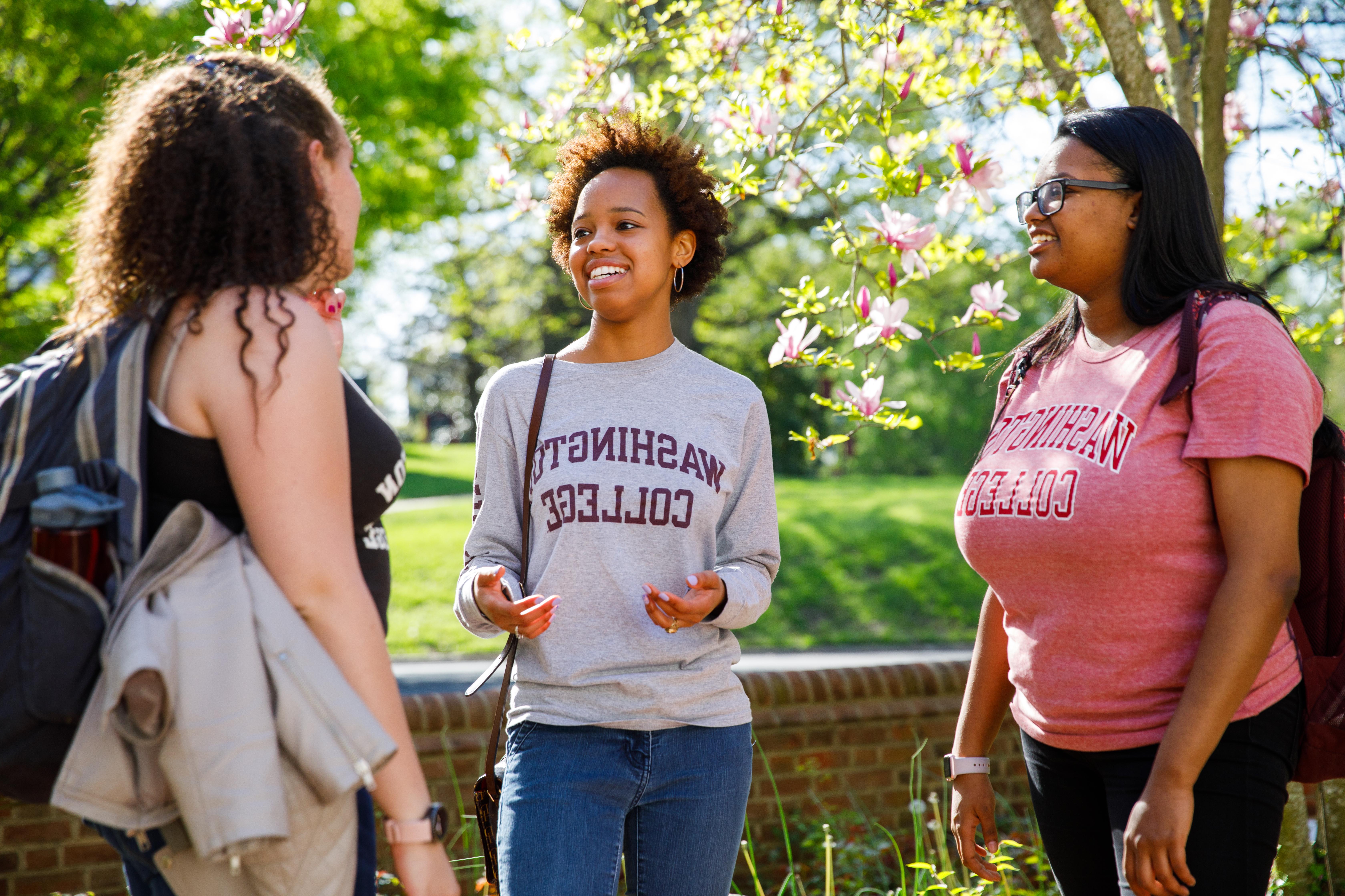 students outside the baseball field, trees blossoming.