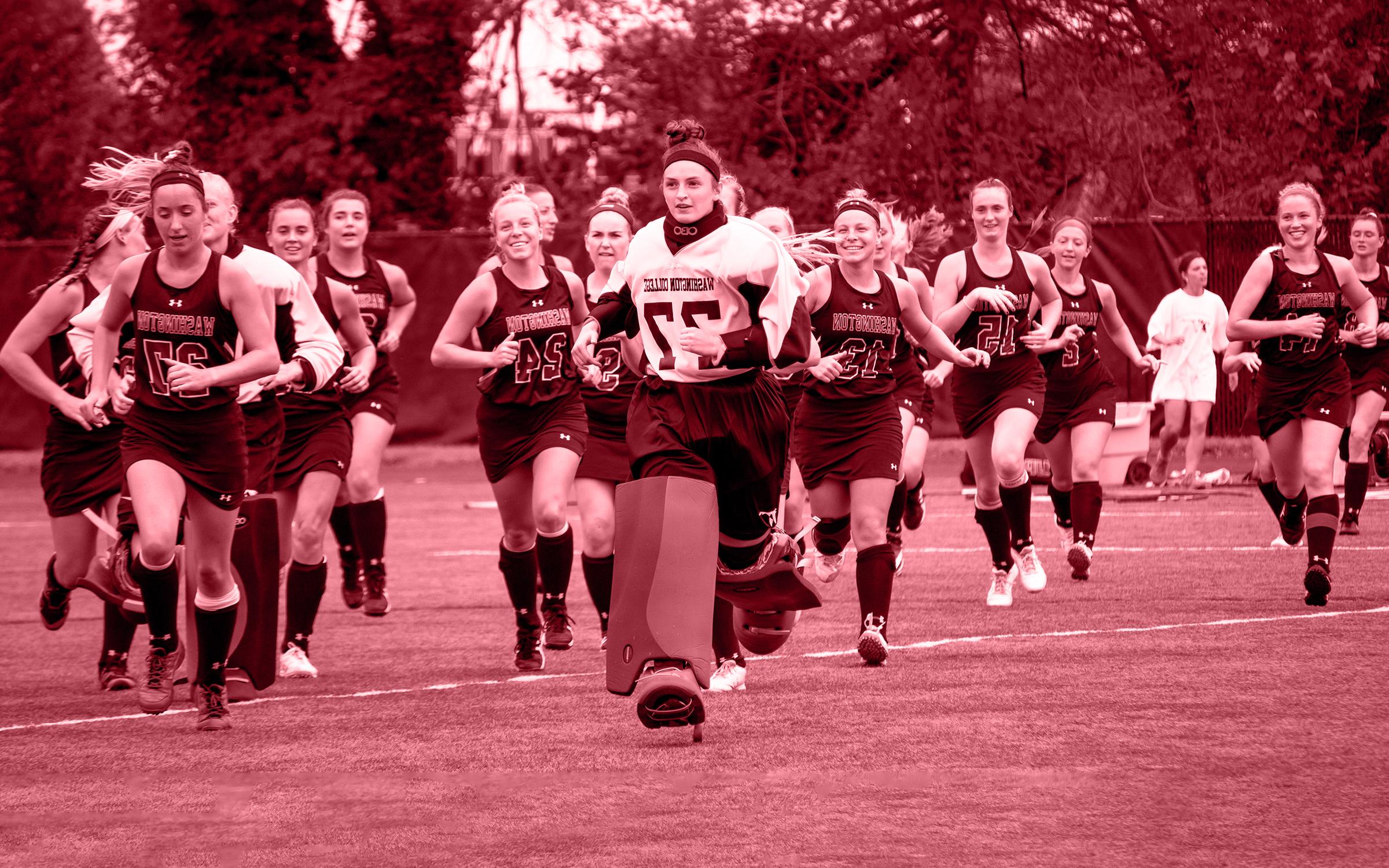 Washington College women's field hockey players running and smiling